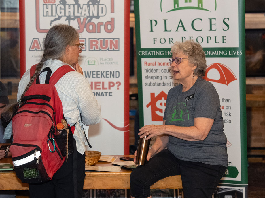 Fay sitting on a counter at the Toronto Impact Investment Fair, talking to a guest.