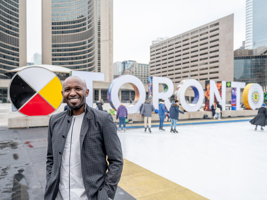 Kizito Musabimana devant un panneau de la ville de Toronto