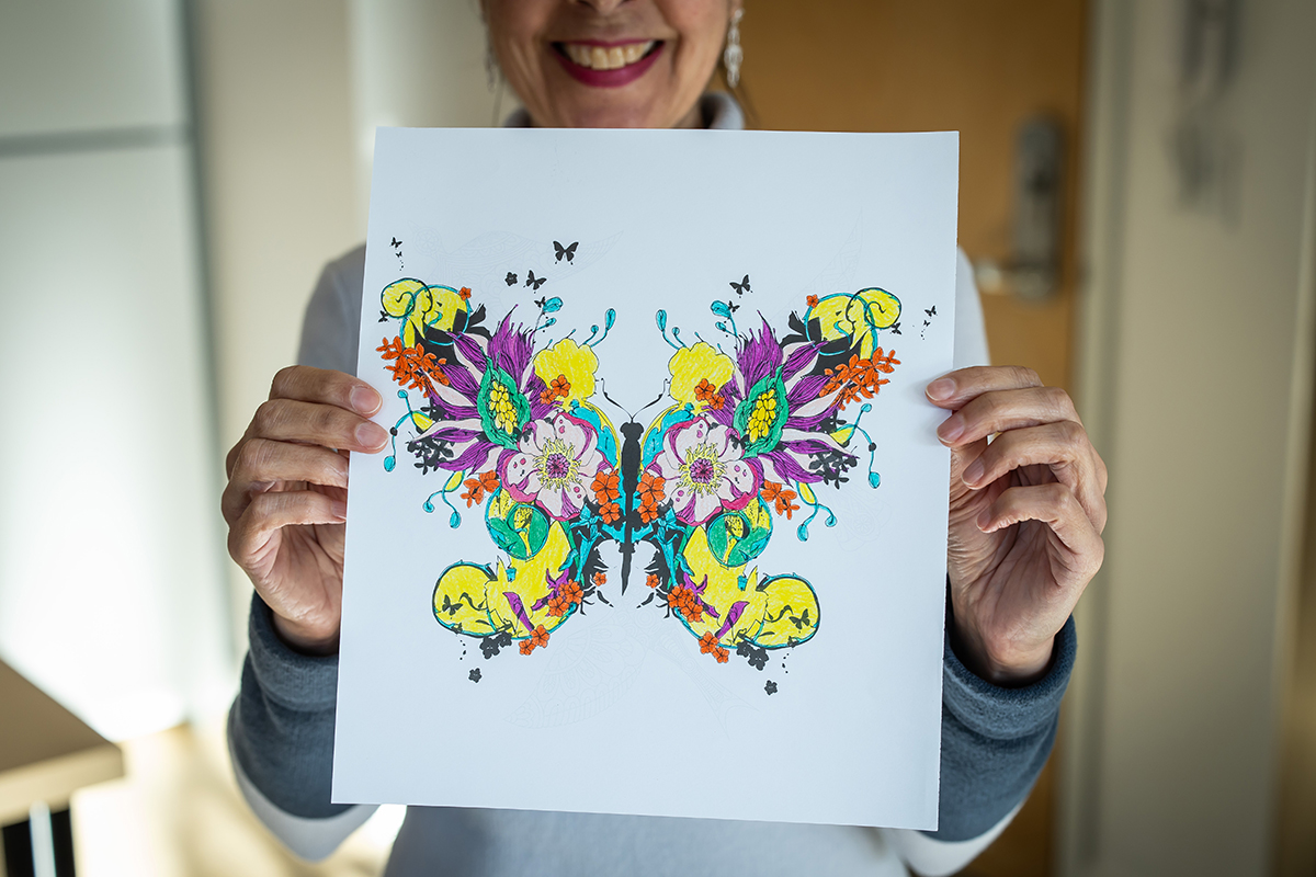 Joëlle holds artwork that was inspired by her new home at La Maison des Papillons.